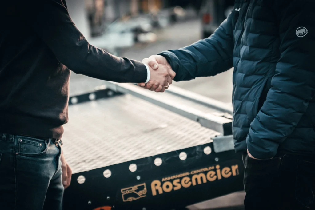 Zwei Personen beim Handschlag vor einem Anhänger von Anhänger Centrum Rosemeier – Symbol für Vertrauen, Beratung und Kundenzufriedenheit